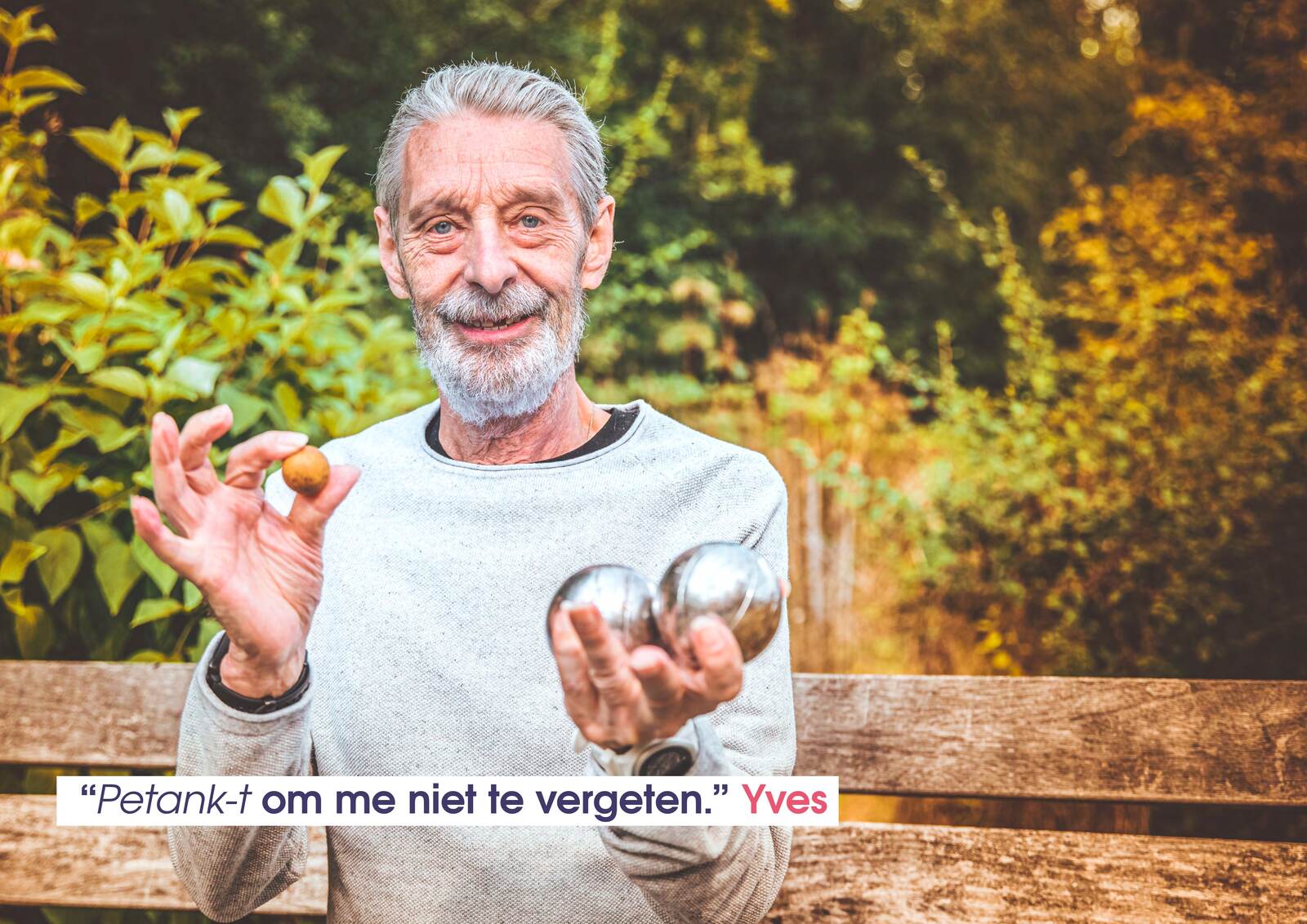 Yves zit op een tuinbank en toont twee petanqueballen en het kleine doelballetje.