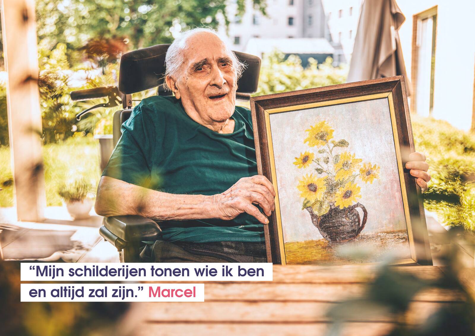 Marcel toont een ingelijst schilderij van gele zonnebloemen bij een raam.